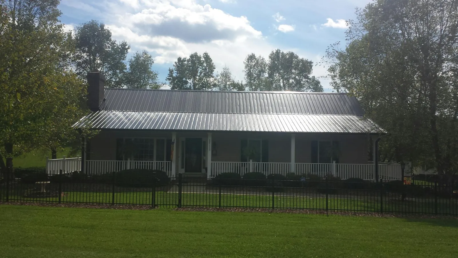 Gray metal roof on a brick ranch with a full width front porch — Gutter Guard Installation work by our crew in Woodville