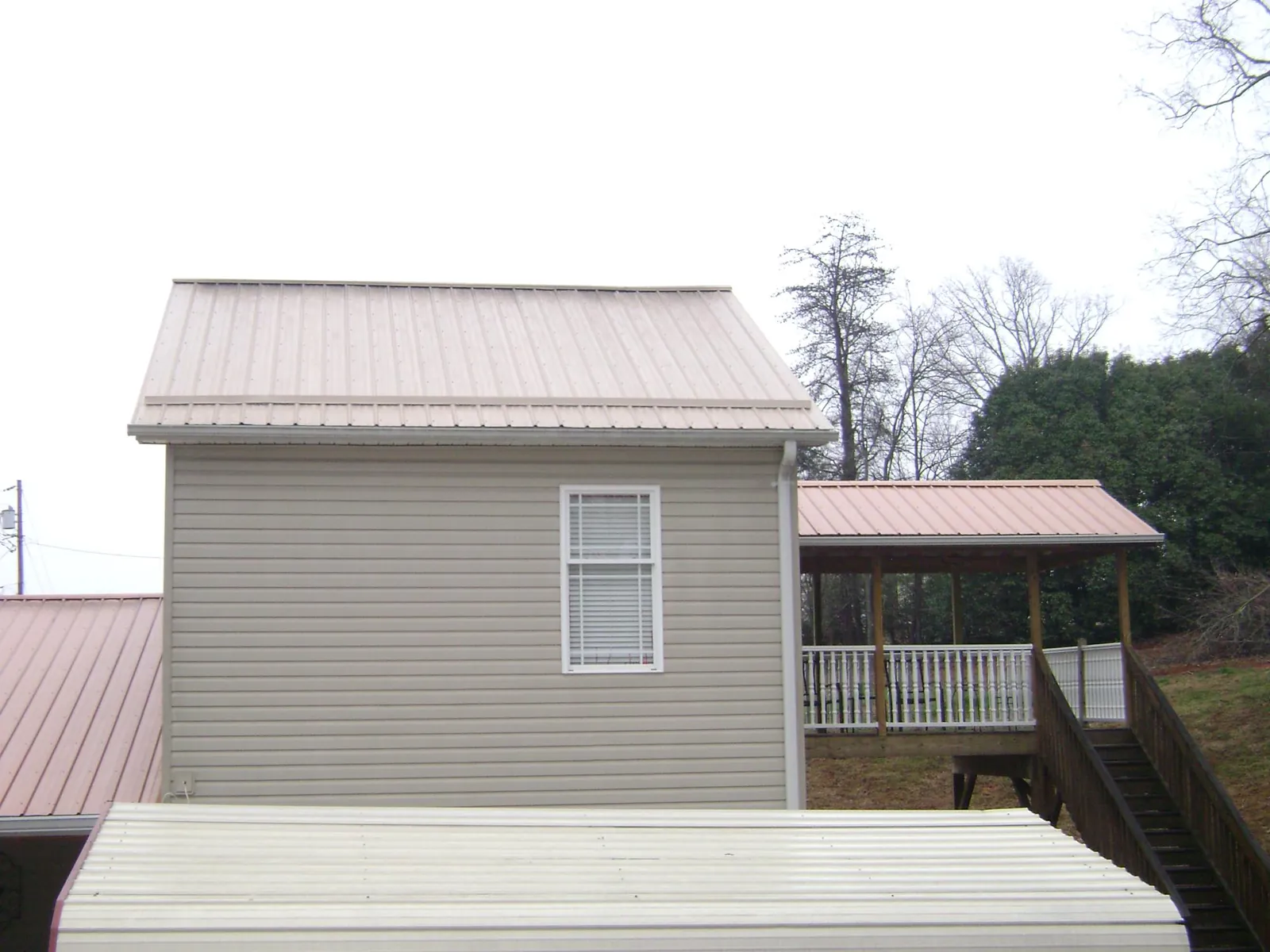 Tan metal roofs on a two story addition and attached porch, from a Roof Replacement job in Woodville